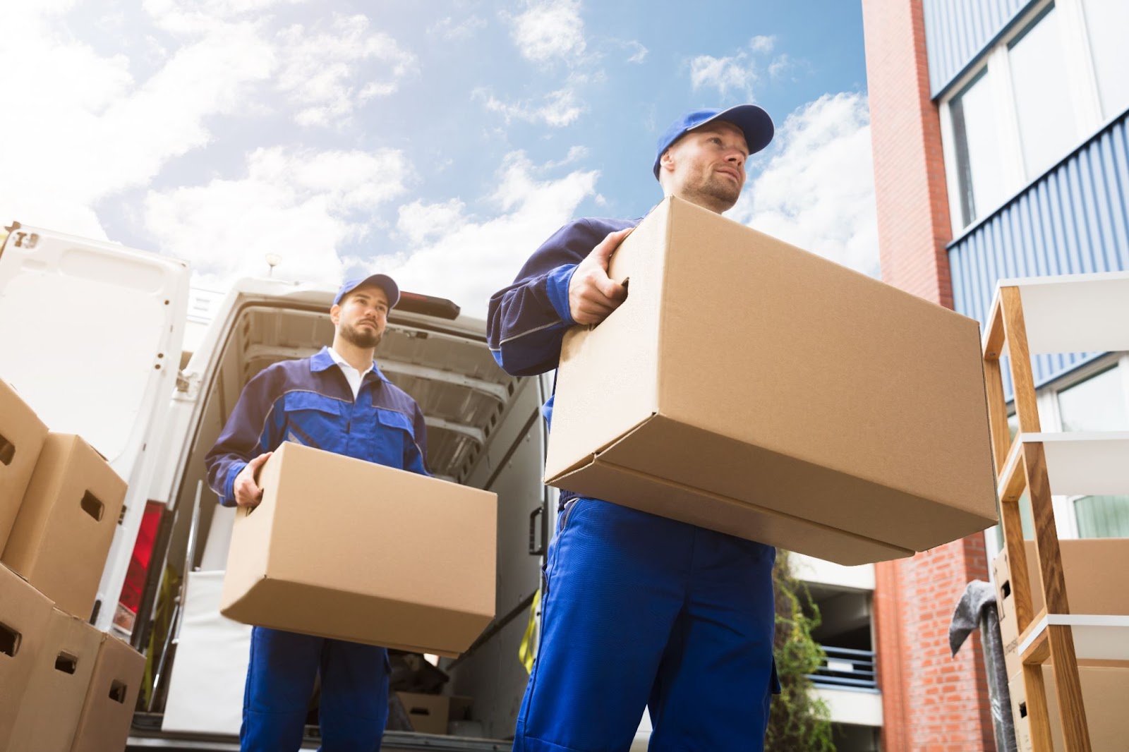 two Franklin Lakes NJ movers in dressed in blue carrying boxes out of a moving van