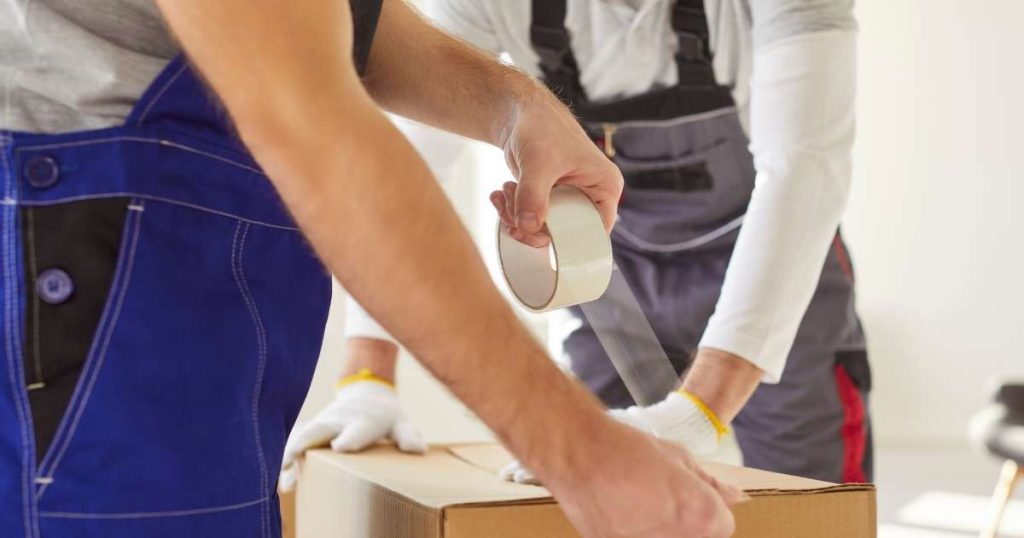 Two movers taping up a box. 