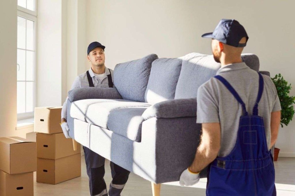 two Ridgefield movers carrying a grey sofa in a customer’s home
