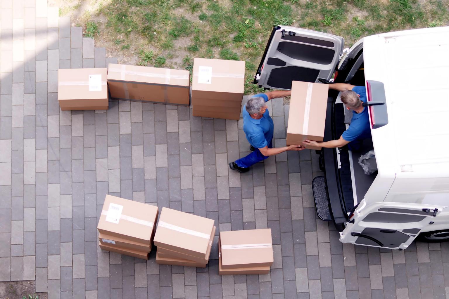A crew of Saddle River movers dressed in blue helping each other tape up boxes
