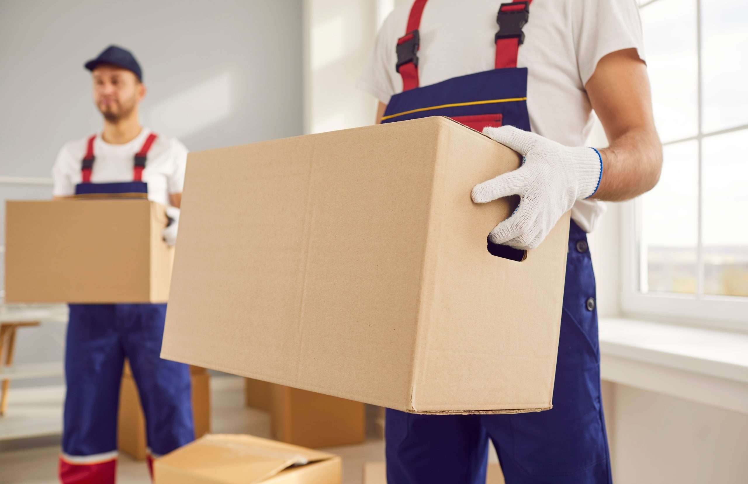 Wyckoff movers in blue overalls holding boxes at a customers home
