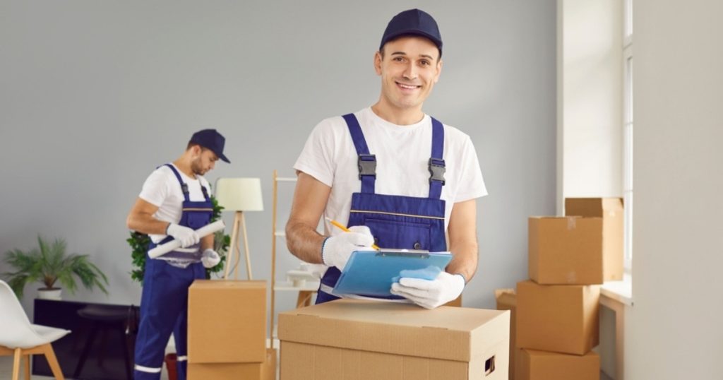 Two professional furniture movers with an Emerson moving company with plastic wrap and a clipboard
