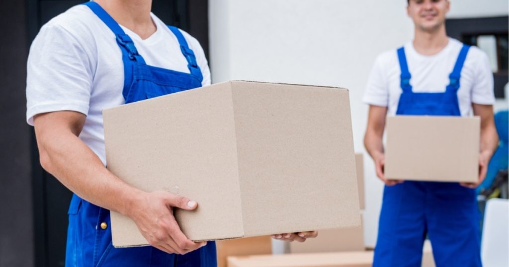 Two uniformed movers in Allendale holding professionally packed moving boxes.