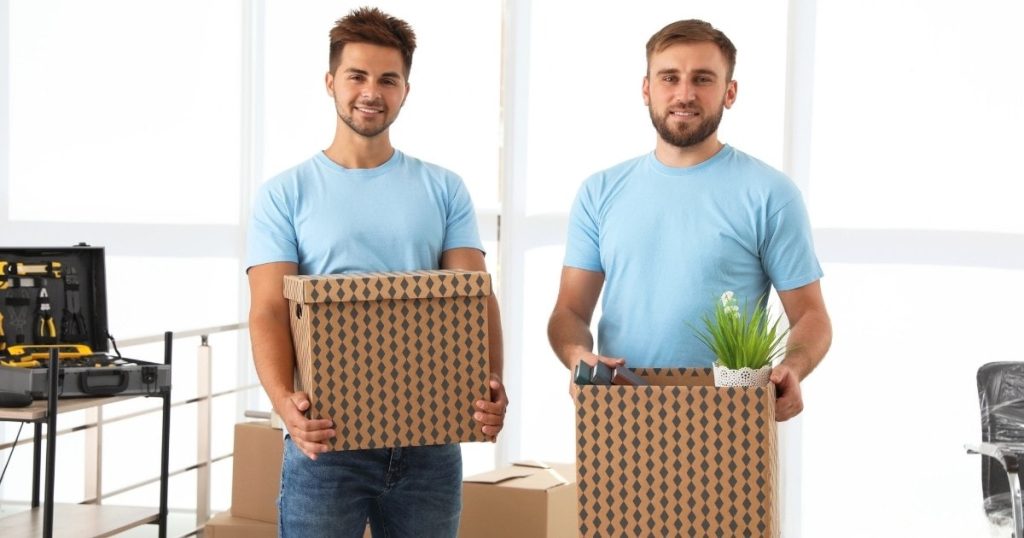 Two movers in Livingston NJ holding boxes in a living room