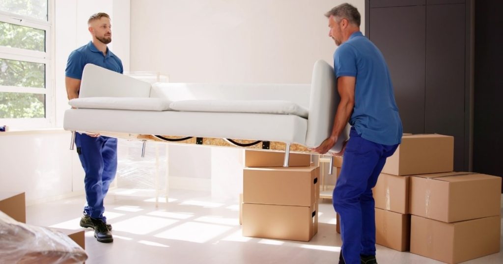 Two furniture movers with a Livingston moving company holding a couch in a living room