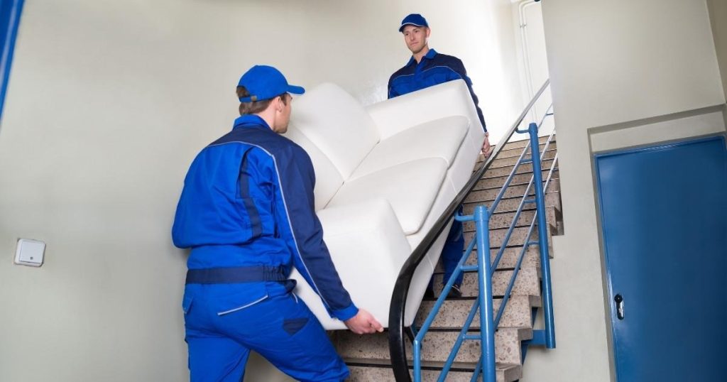 Two movers in Upper Montclair NJ carrying a couch up a flight of stairs