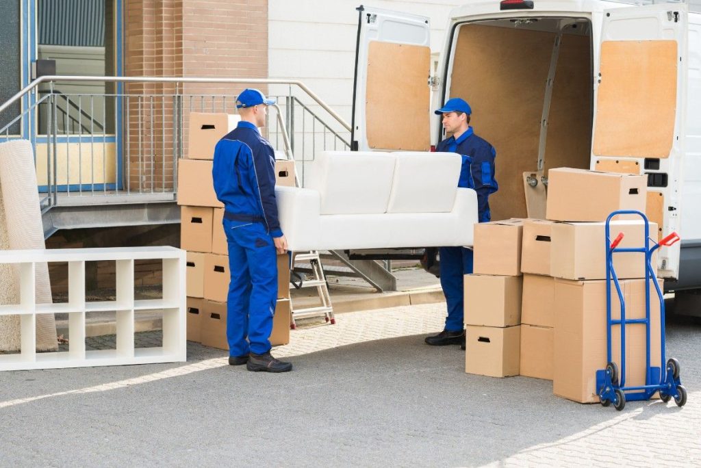 Two movers in Rochelle Park loading a white sofa into the back of a moving truck 